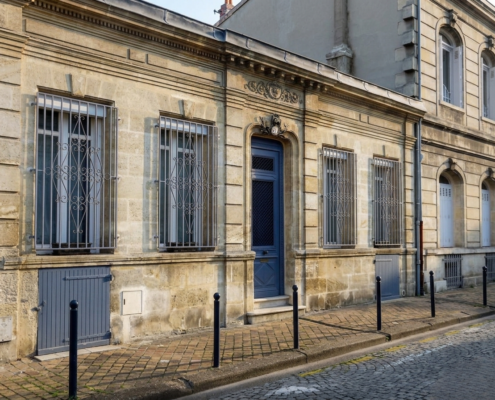 Façade d'échoppe bordelaise en pierre de taille avec porte bleue et grilles forgées - Bordeaux